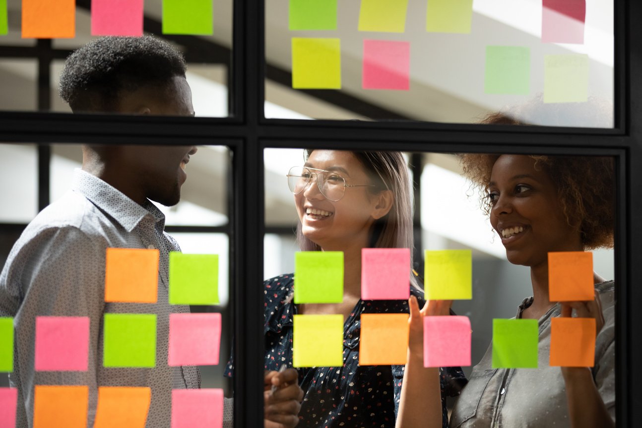 Smiling employees using management tools for work planning.